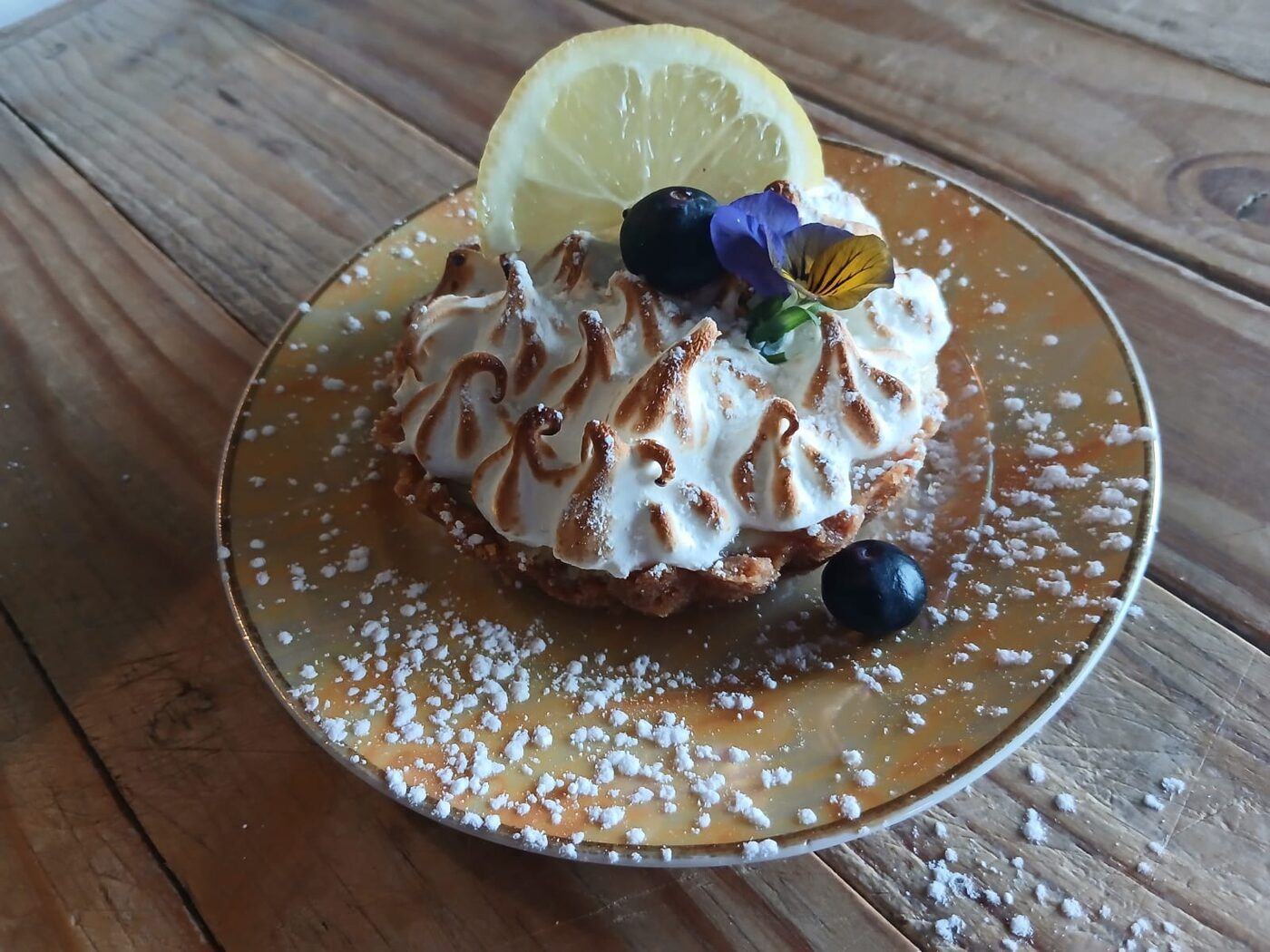 A slice of lemon meringue pie with cream and blueberries